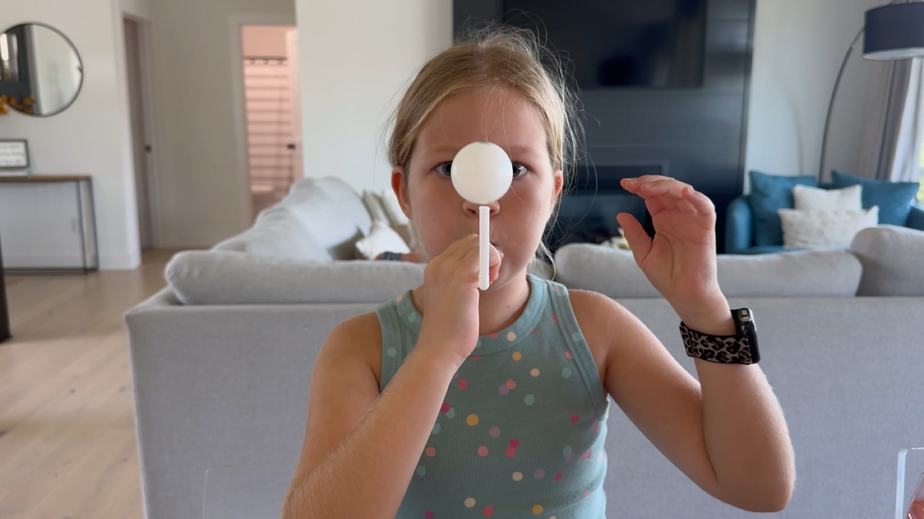 Scarlett holding a white ball on a straw in front of her face