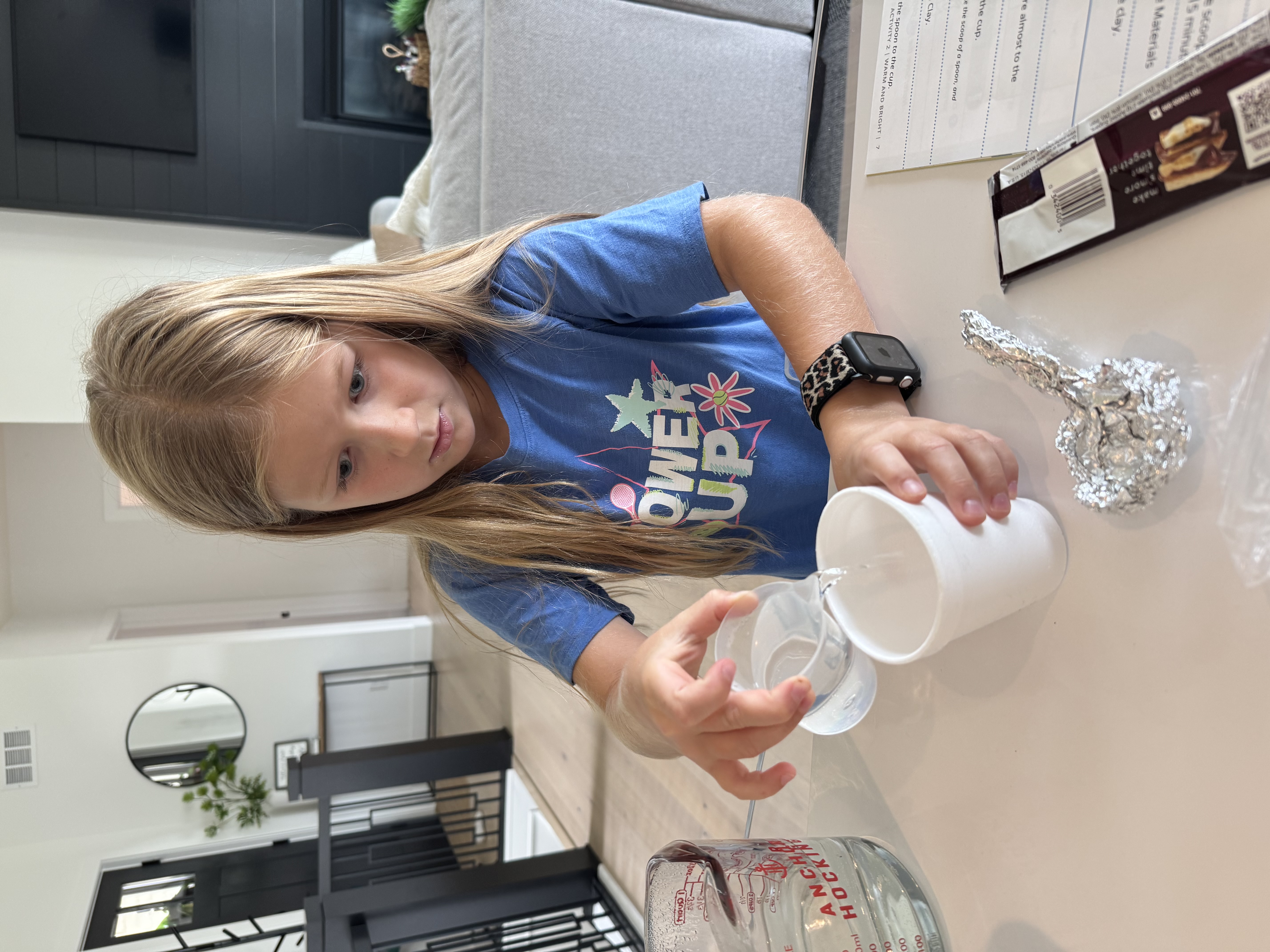 Pouring water into a foam cup beside a foil spoon